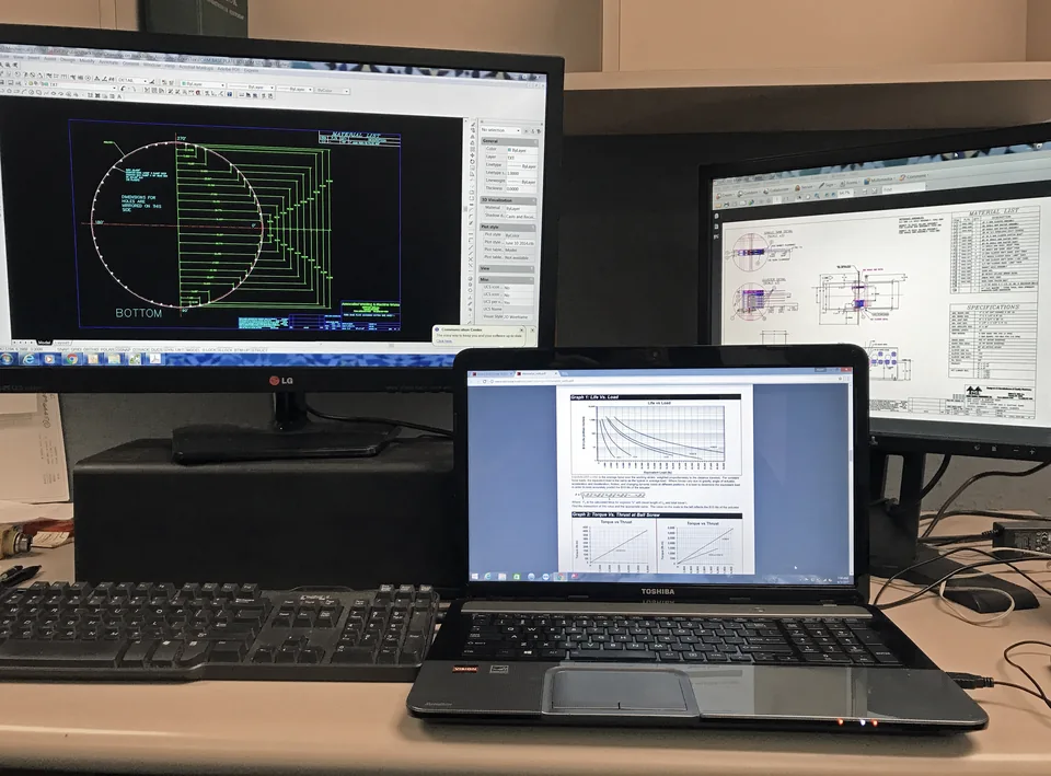 CAD workstation with a technical drawing on a monitor beside a laptop