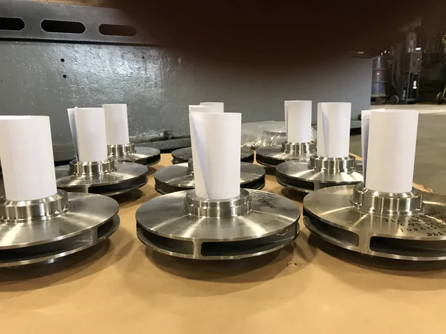 Rows of circular metal components with white upright cylinders