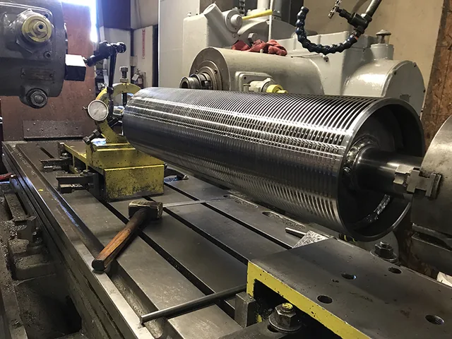 Grooved metal roller positioned on a machine bed
