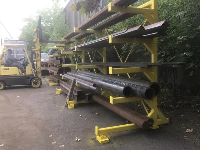 Long fabricated metal sections on yellow supports outdoors