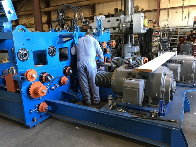 Worker standing beside blue machinery in the shop